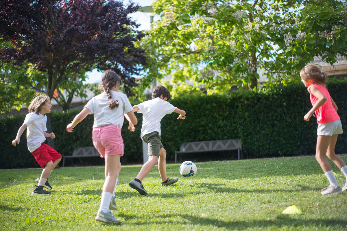 kids playing soccer in the grass